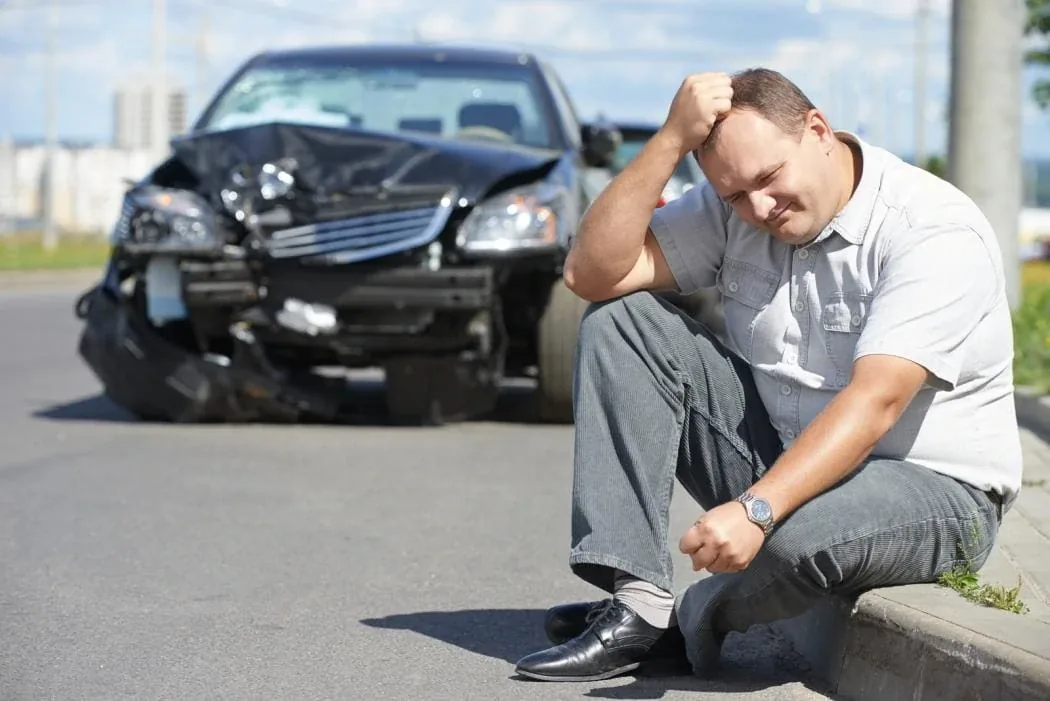 A driver holding their neck in pain after a car accident
