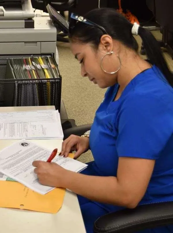 A team member in Florida Wellness scrubs filling out paperwork at a desk